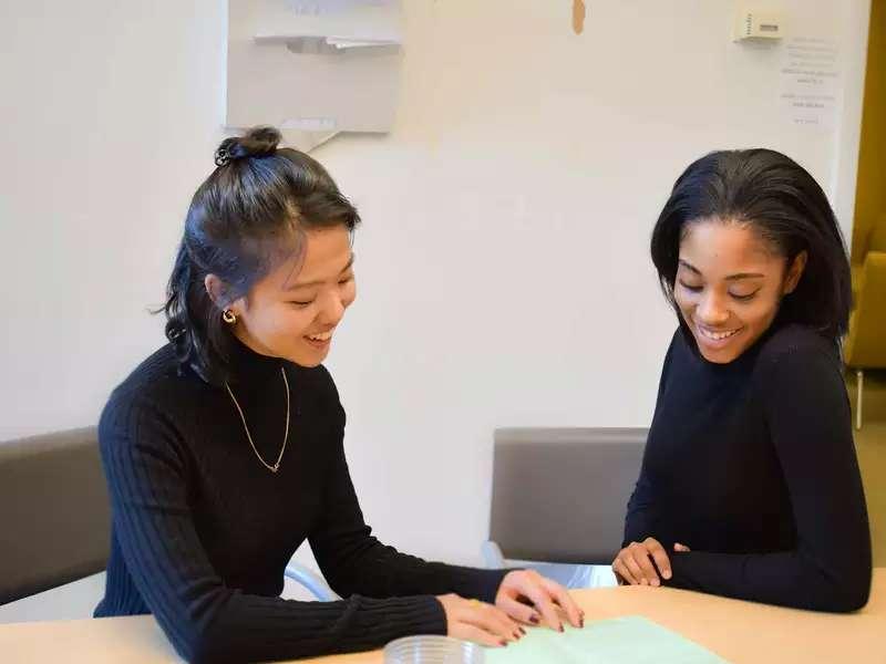 2 students of color working side by side on a writing project